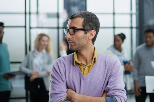 Young handsome businessman looks to the side against the background of his colleagues