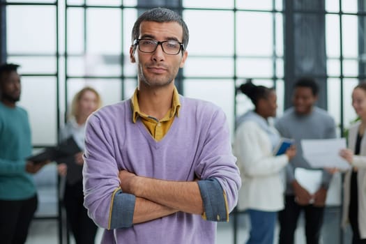 Young handsome businessman looks to the side against the background of his colleagues