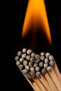 Burning matchsticks in shape of heart against black background