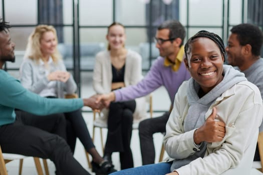 Successful African American manager sitting in front of her colleagues