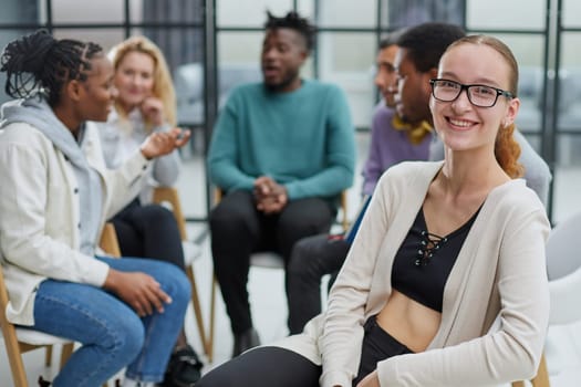 Smiling businesswoman looking at camera at seminar with her colleagues near by