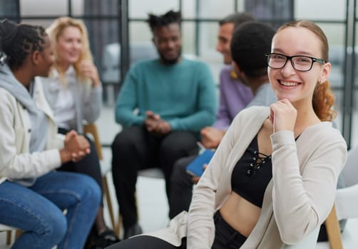 Smiling businesswoman looking at camera at seminar with her colleagues near by