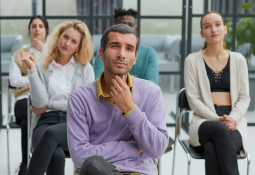 Businessman sitting in front of his colleagues looking at the camera