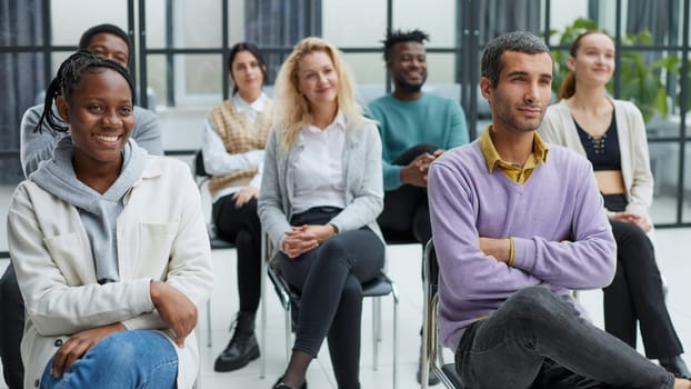 diverse young people sitting on chairs in the conference room.