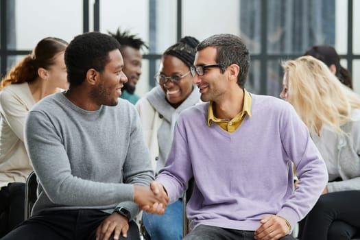 Young people enjoying spending time together on special group therapy. Handsome joyful guy talking jokes and making fun.