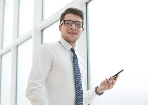 Businessman using smart phone in blurred office space background and copy space
