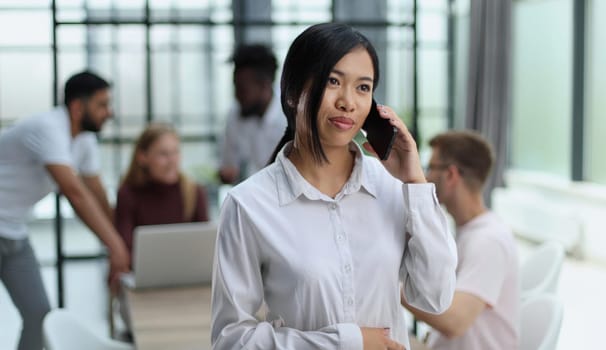 young asian business lady in white shirt talking on the phone in the office