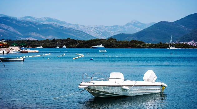 White boat in Adriatic sea, Montenegro with mountains and forest on background. Vessel transportation in beautiful Mediterranean nature in sunny day