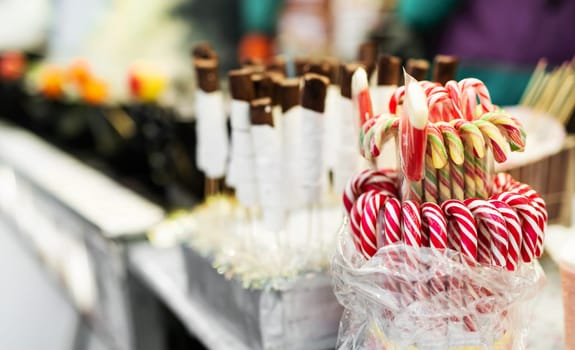 Traditional Christmas lollipop cane candies with red and white stripes at traditional street food festival market. Festive sweets at fair as symbol of Xmas