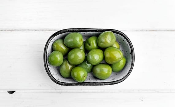 Sweet green olives in plate, mediterranean vegetarian delicatessen. Delicious snack appetizer from Greece