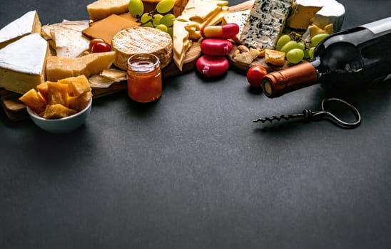 Different kinds of cheese served with wine bottle for gourmet nutrition. Organic parmesan and brie set with grape alcohol delicatessen