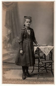 THE CZECHOSLOVAK REPUBLIC - CIRCA 1920s: Vintage photo shows young girl wears Sunday best dress. Antique black white studio portrait.