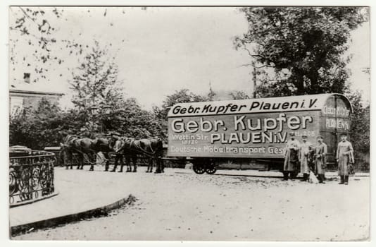 GERMANY - CIRCA 1910s: Vintage photo shows historical removal carriage (van). Removal men pose next to carriage. Antique black white photo.