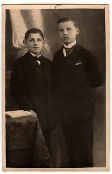 THE CZECHOSLOVAK REPUBLIC - CIRCA 1920s: Vintage photo shows boys wear jackets with handkerchief in the pocket. Antique black white studio portrait. On top of image is imprint of drawing pin.