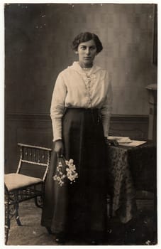 THE CZECHOSLOVAK REPUBLIC - CIRCA 1920s: Vintage photo shows woman holds the flowers. Black white studio photo with sepia tint.