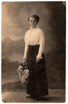 SOLINGEN, GERMANY - CIRCA 1920s: Vintage photo shows woman holds a bunch of lilac. Black white photo with sepia tint.