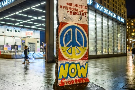 Belin, Germany - 20 December 2022: Peaceful symbol in ukrainian flag colors on a broken Berlin wall in the center of Berlin, Potsdamer Platz.