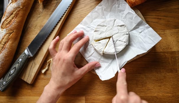 Girl hands cut brie at kitchen. Delicious bakery pastry and camembert for healthy morning meal