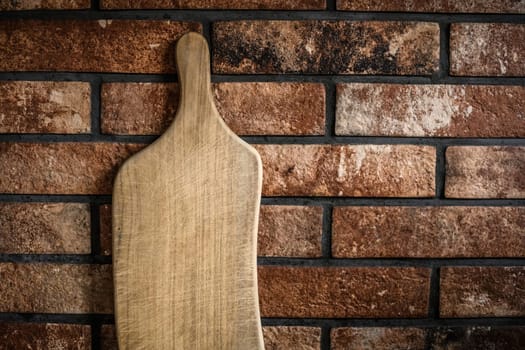 Wooden cutting board at the kitchen against bricks wall