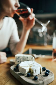 Women drinking a rose wine with french brie cheese plate on a table at home alone