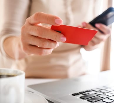Girl with credit card and laptop shopping online. Woman making purchases in internet and paying with debit using computer