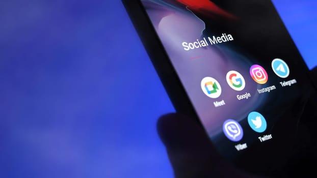 Poznan, Poland - 13 January: Smartphone with apps icons against blue background. Choosing social media application.