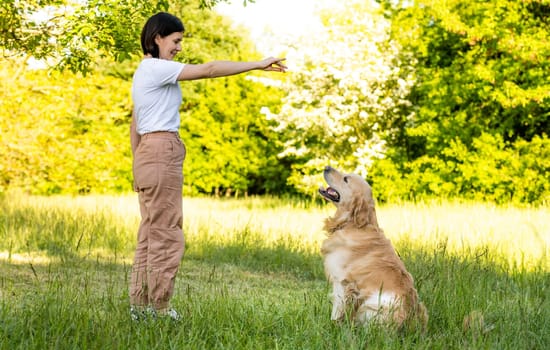 Girl training golden retriever dog outdoors