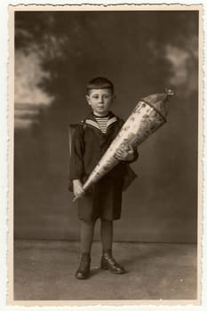 EILENBURG, GERMANY - CIRCA 1920s: Vintage photo shows pupil boy with school cone. Studio photo with sepia tint.