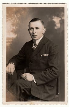 EILENBURG, GERMANY - CIRCA 1920s: Vintage photo shows young man poses in a photography studio. Antique black & white studio portrait.