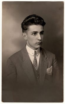 LIBEREC (REICHENBERG), THE CZECHOSLOVAK REPUBLIC - CIRCA 1920s: Vintage photo shows young man wears jacket, tie and handkerchief in pocket. Antique black & white studio portrait.