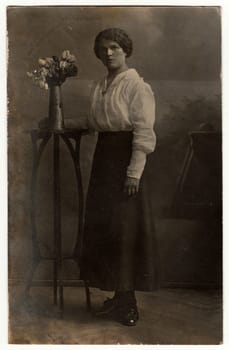 AUSTRIA-HUNGARY - CIRCA 1910s: Vintage photo shows woman poses in a photography studio. Black white antique studio portrait.