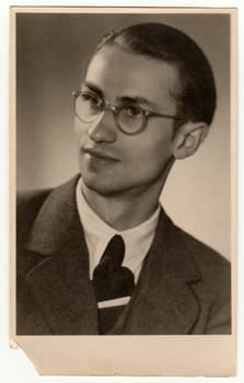 THE CZECHOSLOVAK REPUBLIC - CIRCA 1940s: Vintage photo shows young man with glasses. Black white antique studio portrait.