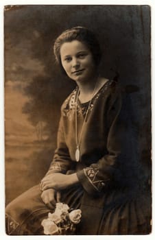 AUSTRIA-HUNGARY - CIRCA 1910s: Vintage photo shows woman holds white roses. Photo with dark sepia tint. Black white studio portrait.