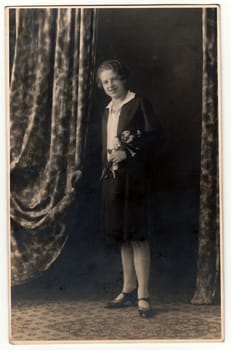 HEJNICE (HAINDORF), THE CZECHOSLOVAK REPUBLIC - CIRCA 1930s: Vintage photo shows woman with a bunch of flowers, poses in a photography studio. Photo with dark sepia tint. Black white studio portrait.