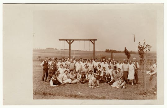 THE CZECHOSLOVAK REPUBLIC - JUNE 15, 1930: Vintage photo shows a group of people outdoors. Horizontal bar for rope- climbing is in the background. Black white photo.