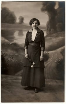 AUSTRIA-HUNGARY - CIRCA 1910s: Vintage photo shows woman holds white roses. Photo with dark sepia tint. Black white studio portrait.