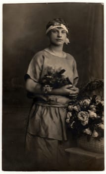 THE CZECHOSLOVAK REPUBLIC - CIRCA 1930s: Vintage photo shows woman with bunch of flowers poses in a photography studio. Photo with dark sepia tint. Black white studio portrait.