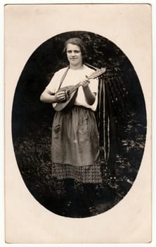 GERMANY - 1930s: Vintage photo shows a woman plays the mandolin outdoors. Photo is oval shape. Black white antique photo.