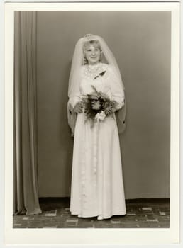 THE CZECHOSLOVAK SOCIALIST REPUBLIC - CIRCA 1980: Vintage photo shows bride wears veil and she holds bouquet of gerberas. Black white antique photo.