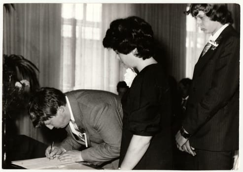 THE CZECHOSLOVAK SOCIALIST REPUBLIC - CIRCA 1980: Vintage photo shows wedding's witness (best man) as he makes signature after wedding ceremnony. Black white antique photo.