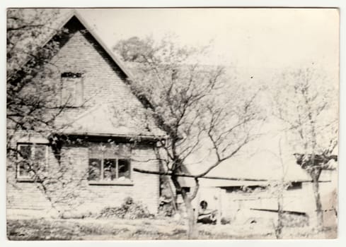 THE CZECHOSLOVAK SOCIALIST REPUBLIC - CIRCA 1960s: Vintage photo shows village house in the garden. Black white antique photo.