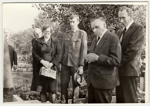 THE CZECHOSLOVAK SOCIALIST REPUBLIC - CIRCA 1980s: Vintage photo shows people after funeral. They stay at the grave of kin. Black white antique photo.