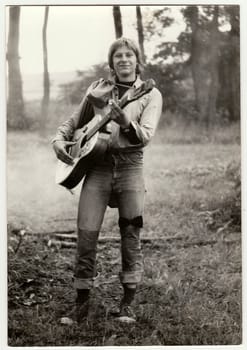 THE CZECHOSLOVAK SOCIALIST REPUBLIC - CIRCA 1980s: Vintage photo shows young hiker plays the guitar outdoors. Antique black white photo.