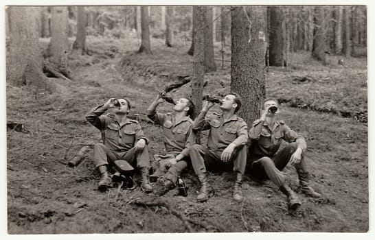 THE CZECHOSLOVAK SOCIALIST REPUBLIC - CIRCA 1970s: Vintage photo shows soldiers pose with beer bottles outddors. Black & white antique photo.