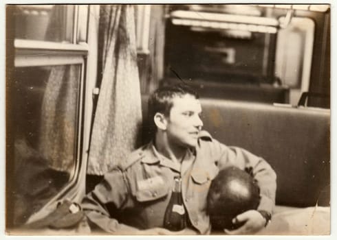 THE CZECHOSLOVAK SOCIALIST REPUBLIC - SEPTEMBER 9, 1981: Vintage photo shows man with bottle of wine sits in railway carriage. Black & white antique photo.