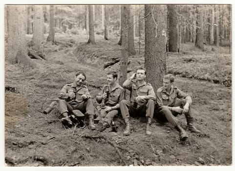 THE CZECHOSLOVAK SOCIALIST REPUBLIC - CIRCA 1970s: Vintage photo shows soldiers pose with beer bottles outdoors. Black & white antique photo.