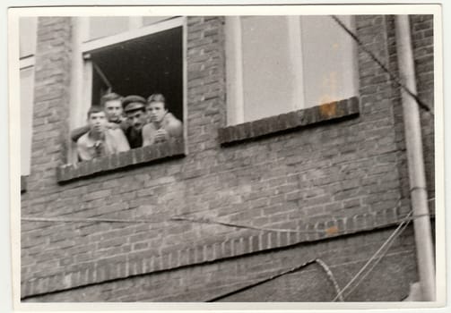 THE CZECHOSLOVAK SOCIALIST REPUBLIC - CIRCA 1970s: Vintage photo shows soldiers pose in barracks`s window. Black & white antique photography.