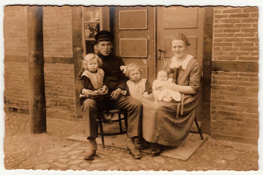 GERMANY - CIRCA 1930s: Vintage photo shows rural family sits in front of house. Black white antique photography.