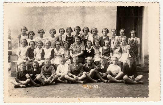 SOBOTKA, THE CZECHOSLOVAK REPUBLIC - 1938: Vintage photo shows a group of schoolmates and female teacher. Black white photo.