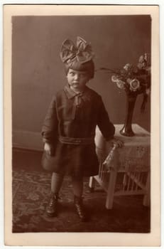 HAMBURG, GERMANY - CIRCA 1930s: Vintage photo shows a small girl wears hair ribbon, poses indoors. Black white studio photography.